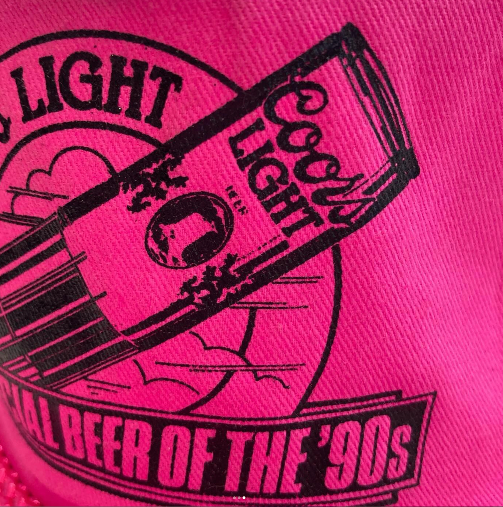 Close-up view of the Coors Light logo on the hot pink hat, highlighting the iconic mountain design and 'Official Beer of the '90s' slogan.